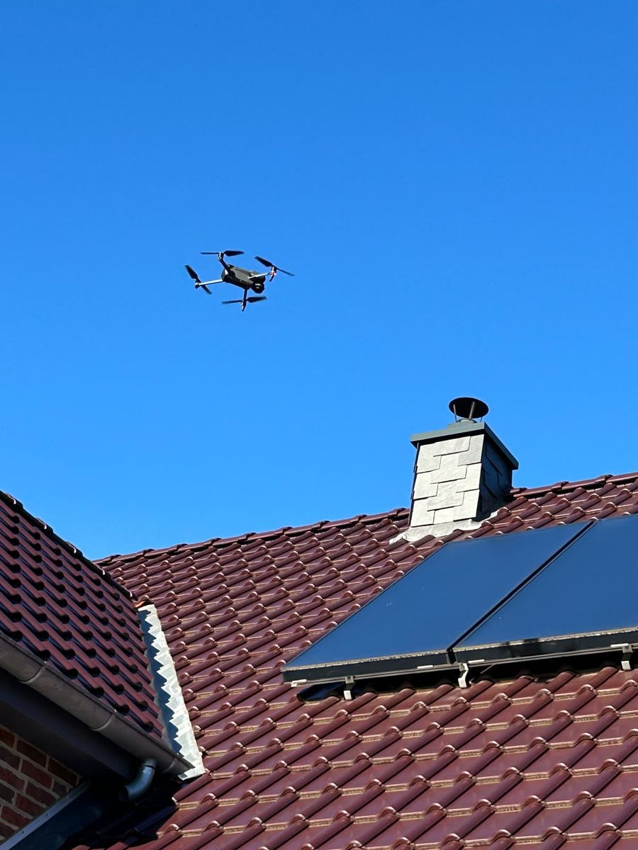 Die Drohne fliegt über einem Dach mit Solarkollektor und Schornstein